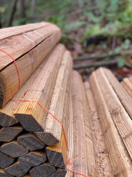 A bundle of hand cleft diamond staves made from chestnut wood, with visible natural grain and coloring.