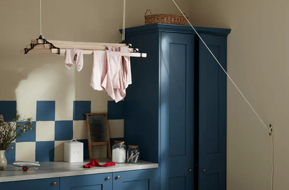 Laundry room with hanging clothes, blue cabinets, and checkered wall.