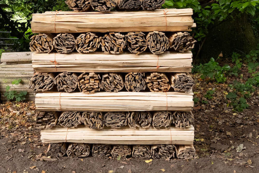 A bundle of hand riven chestnut laths, split from locally sourced timber, stacked neatly.