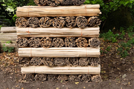 A bundle of hand riven chestnut laths, split from locally sourced timber, stacked neatly.