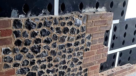 A pack of 10 SureCav25 cavity spacer backing boards, with a visible honeycomb structure, in front of a brick wall.